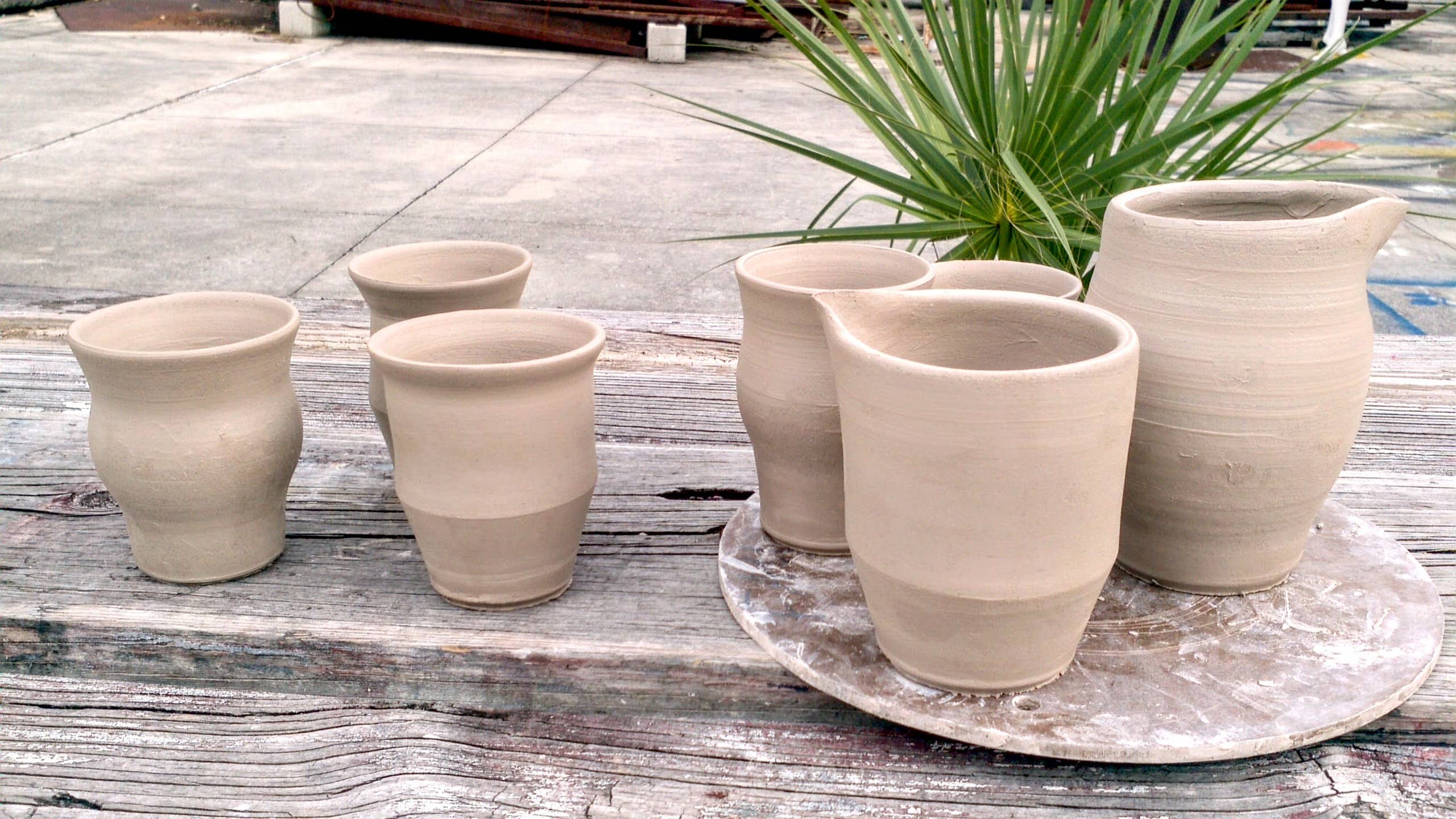 Handmade ceramic vessels drying on a wooden worktable